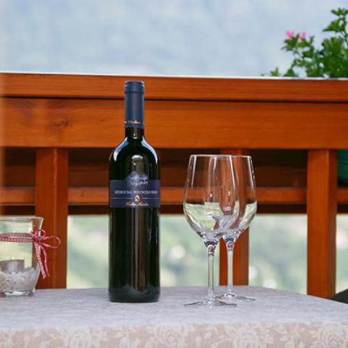 Weingläser und eine Flasche Rotwein auf einem kleinen Tisch auf den Balkon